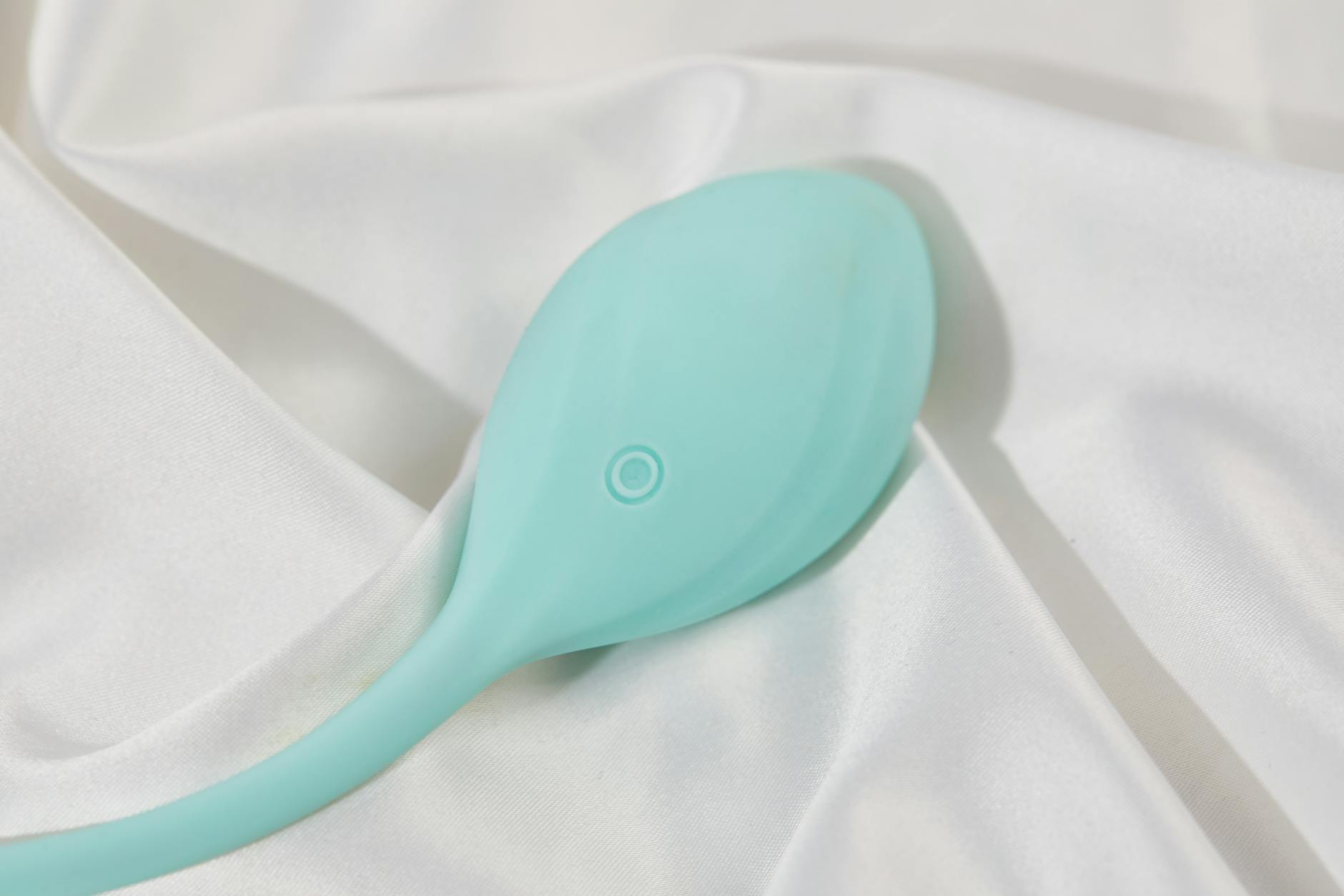 A teal silicone vibrator resting on clean white fabric, ready for care and maintenance.