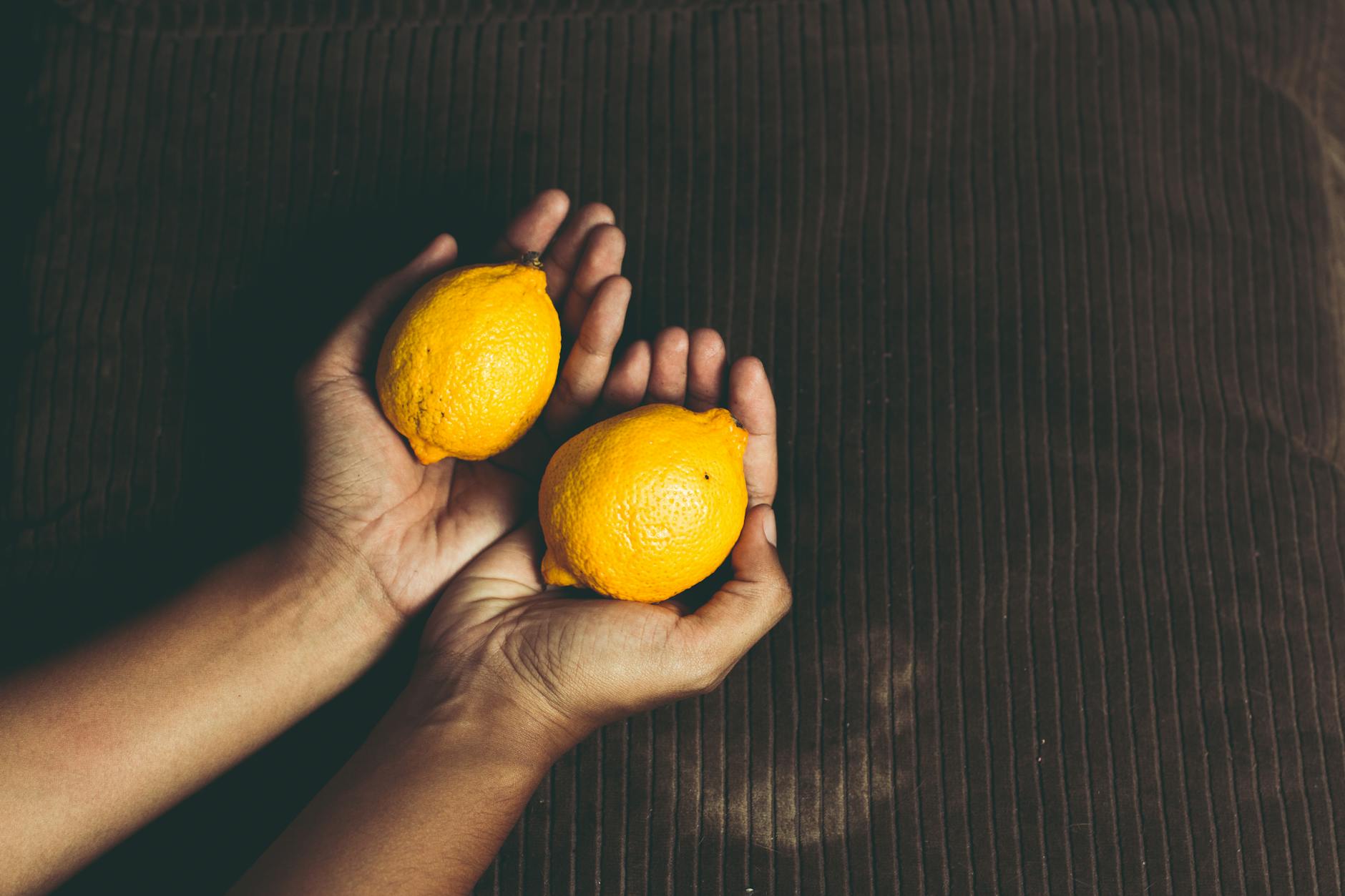 Hands holding fresh lemons, symbolizing the precision and care of lemon vibrators
