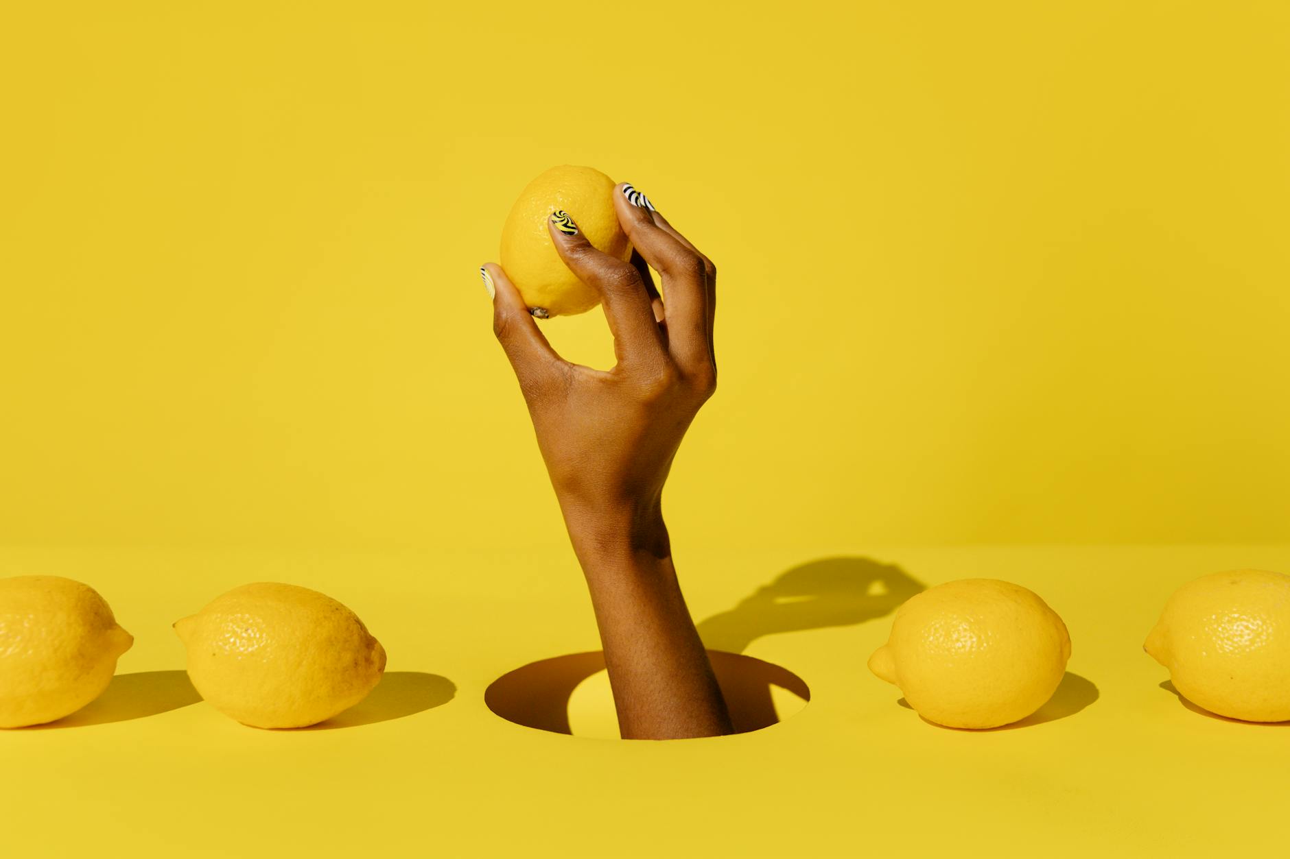 A hand holding a lemon against a vivid yellow background, symbolizing fresh reconnection and awakening