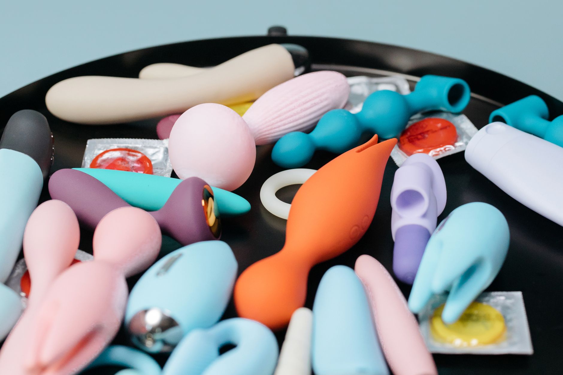 A vibrant collection of various sex toys including lemon vibrators on a black tray, featuring diverse shapes and colors.